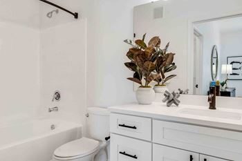 a white bathroom with a sink and a toilet and a bath tub